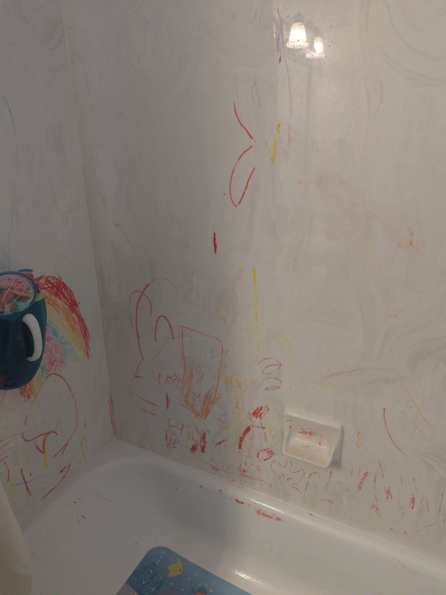 Crayon-covered tub surround before and after cleaning — before