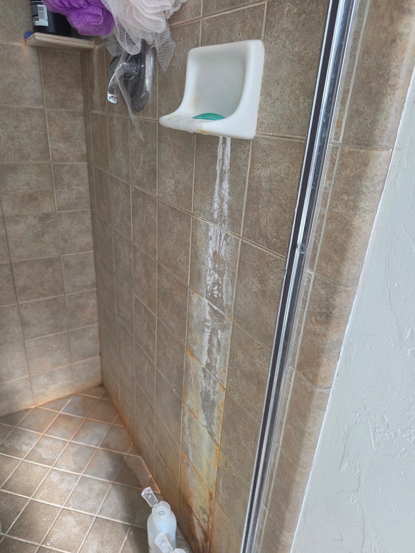 Tiled shower before and after deep cleaning — before